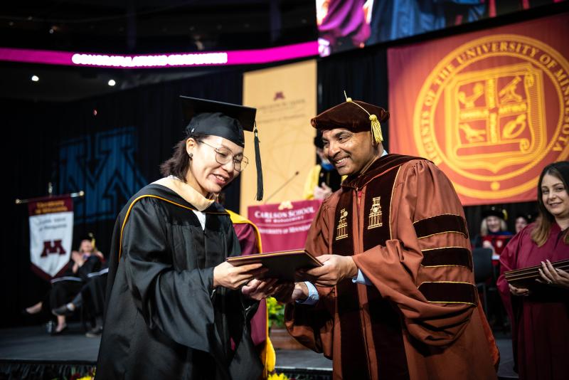 A graduate student from the CHEMBA program receives her diploma from Alok Gupta at the 2022 commencement ceremony
